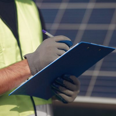 Engineer in a white helmet. Man near solar panel. Worker with a folder.
